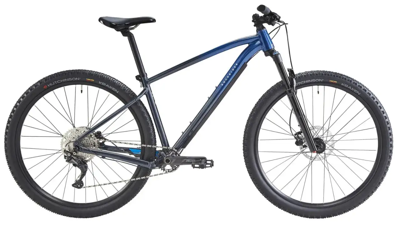 Granatowy rower górski Rockrider z oponami Hutchinson Kraken. Idealny do pokonywania trudnych tras.