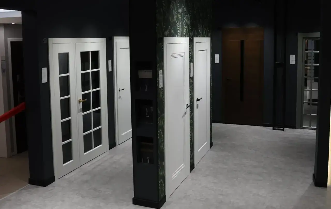 Salon drzwi w Łodzi: białe drzwi dwuskrzydłowe z przeszkleniem, białe drzwi jednolite, brązowe drzwi wejściowe.