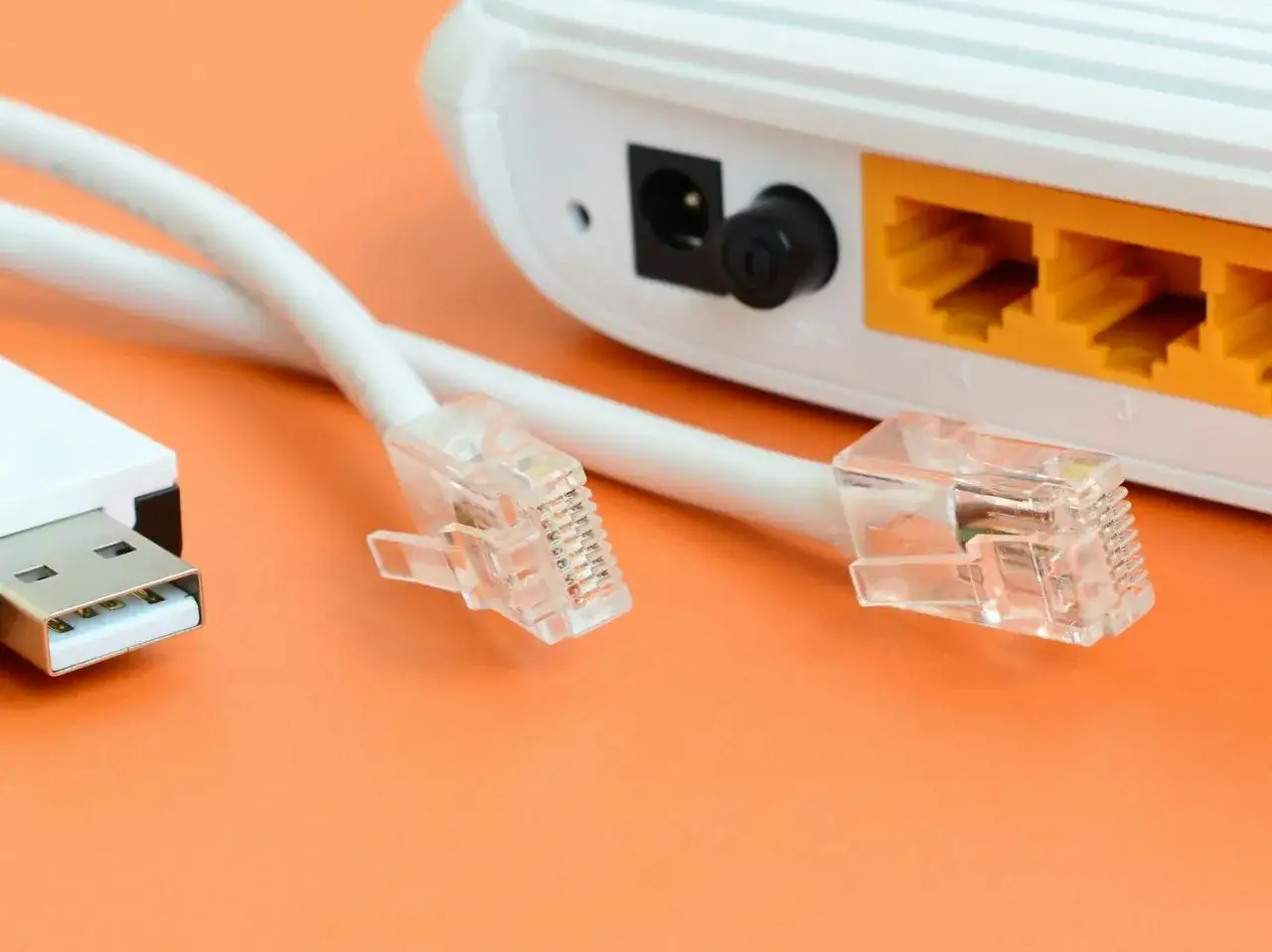 Router z kablami Ethernet i USB na pomarańczowym tle.
