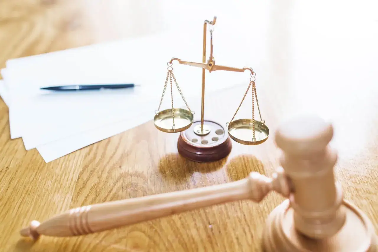 Młotek sędziowski, waga sprawiedliwości i dokumenty na drewnianym stole. Zastanawiasz się, jak odroczyć sprawę w sądzie?