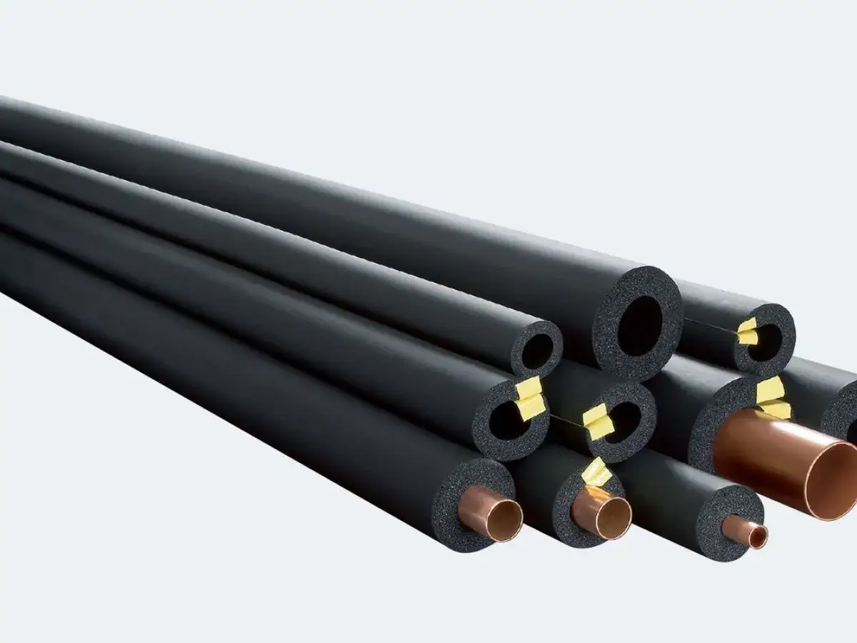 Stos izolacyjnych rur z czarnej pianki z widocznymi miedzianymi rurkami w środku.