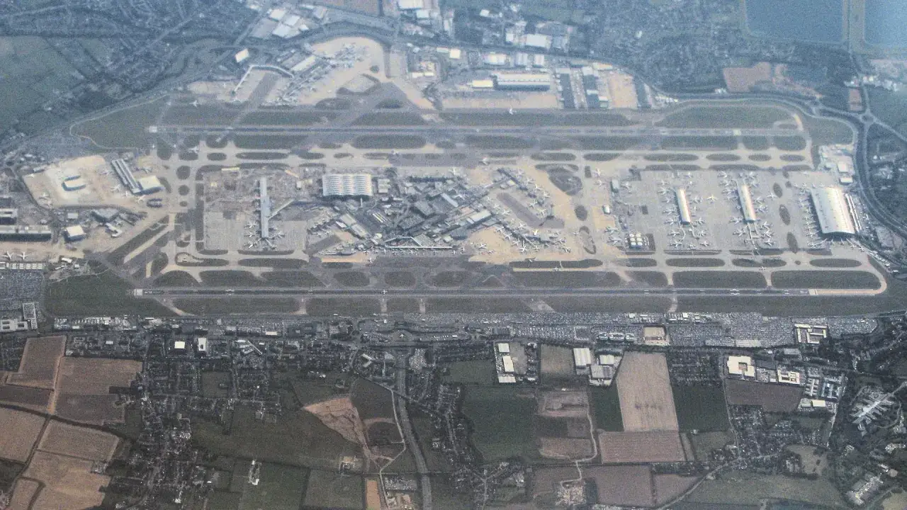 Widok z lotu ptaka na port lotniczy Londyn Heathrow z licznymi samolotami na płycie lotniska i pasami startowymi.