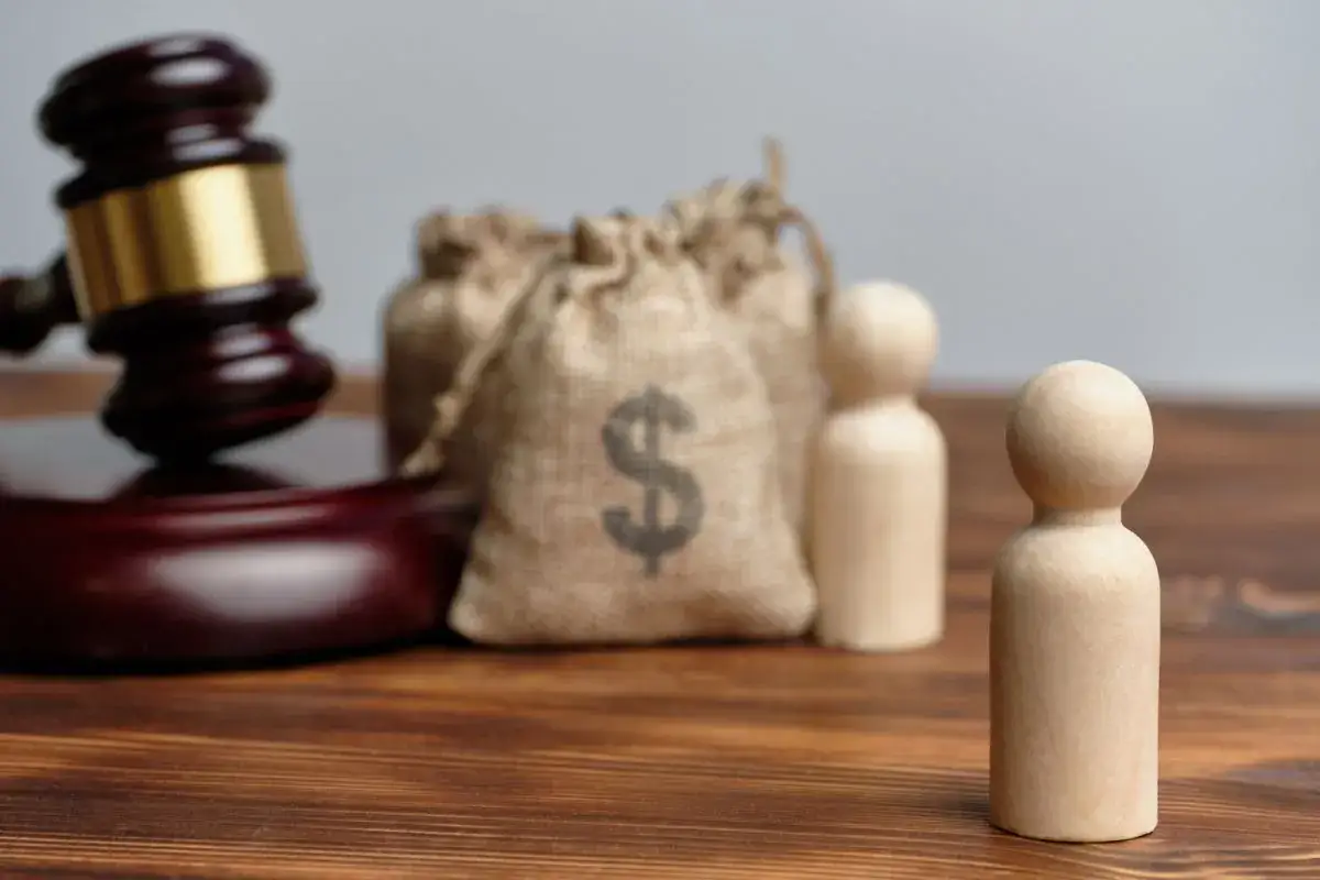 Młot sędziowski, sakiewki z pieniędzmi i drewniane figurki symbolizują obecność uczestników na rozprawie o stwierdzenie nabycia spadku.