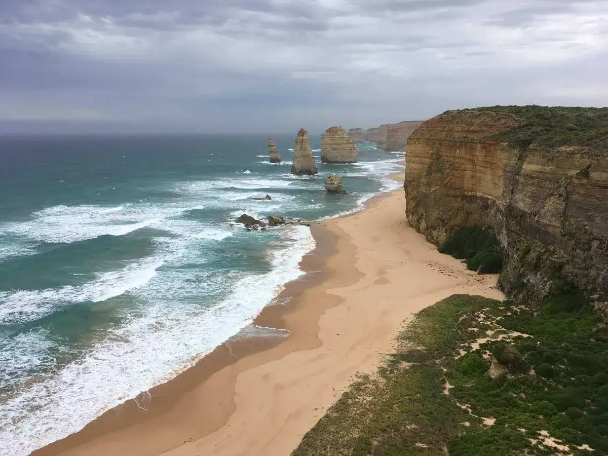 Piękne klify i plaża nad oceanem, kiedy w Australii jest lato. Woda jest turkusowa, a fale rozbijają się o brzeg.