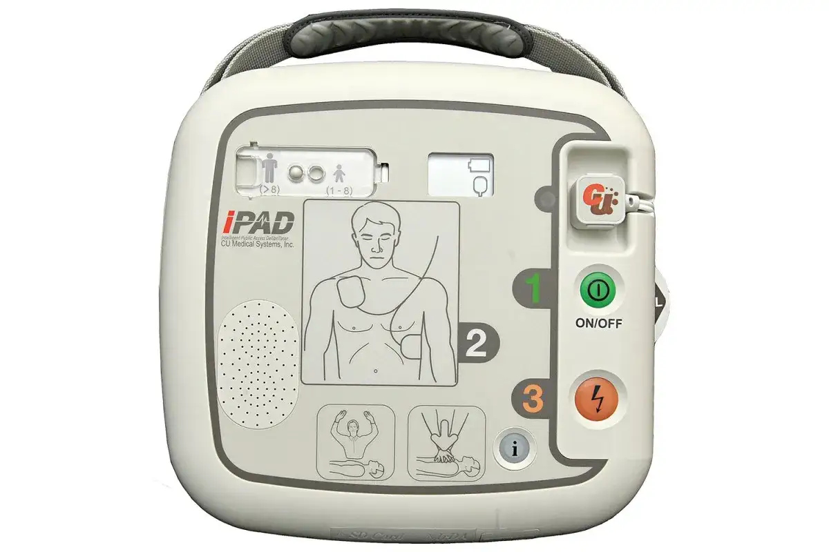 Automatyczny defibrylator zewnętrzny (AED) iPAD w kolorze białym, z widocznymi przyciskami i instrukcjami.