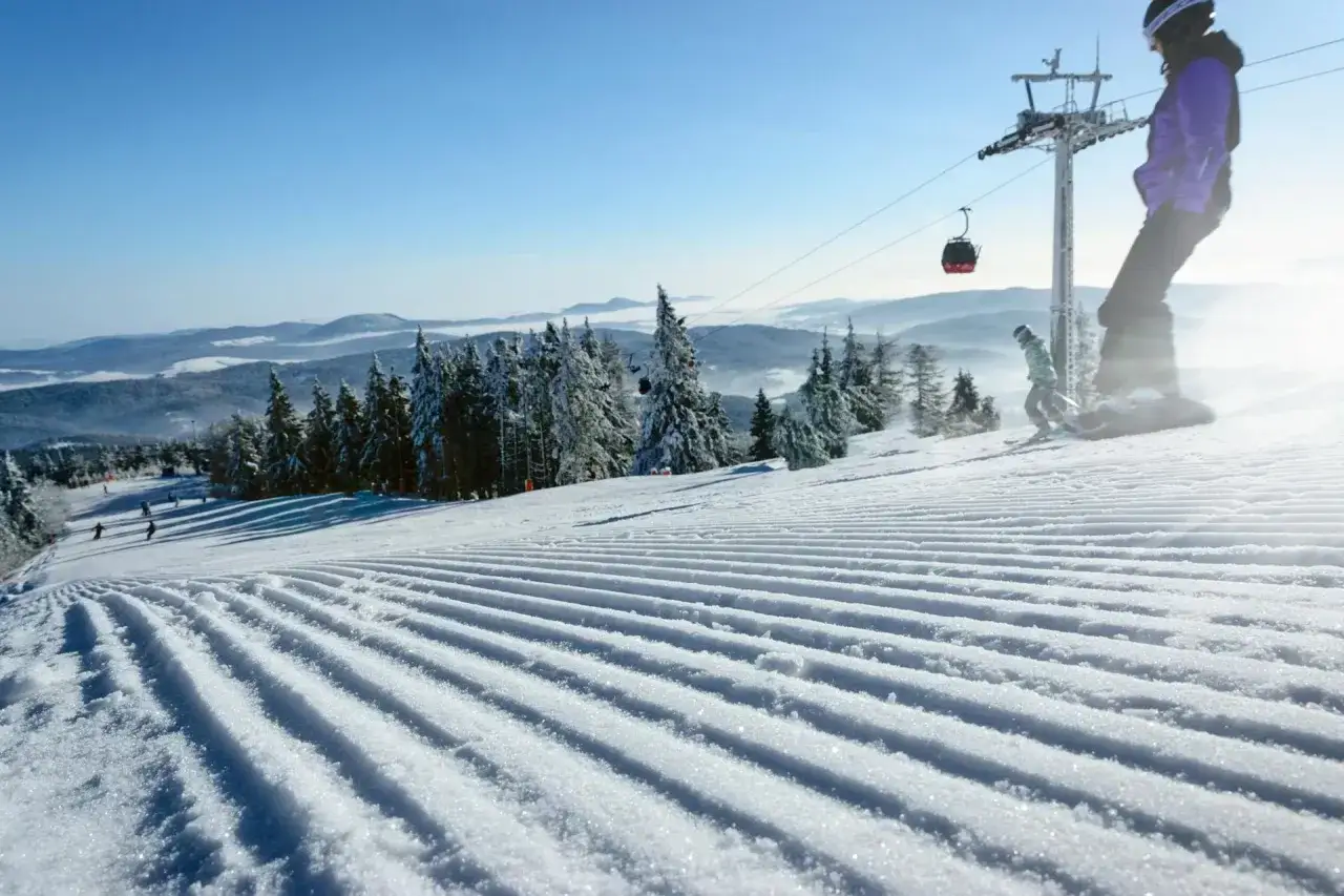 Przygotowany stok narciarski z widokiem na góry i kolejką linową.