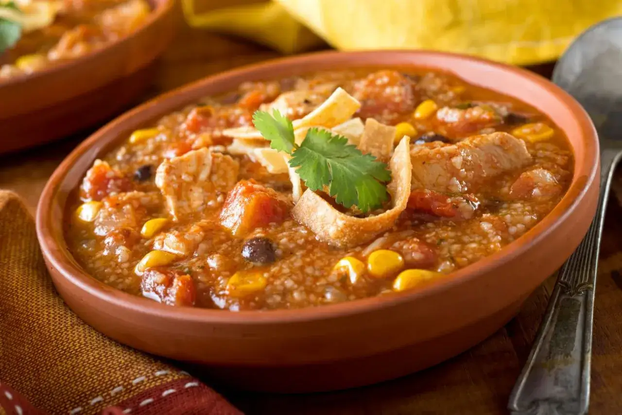 Gęsta zupa z grilla z kurczakiem, kukurydzą i fasolą, ozdobiona chrupiącymi nachos i kolendrą.