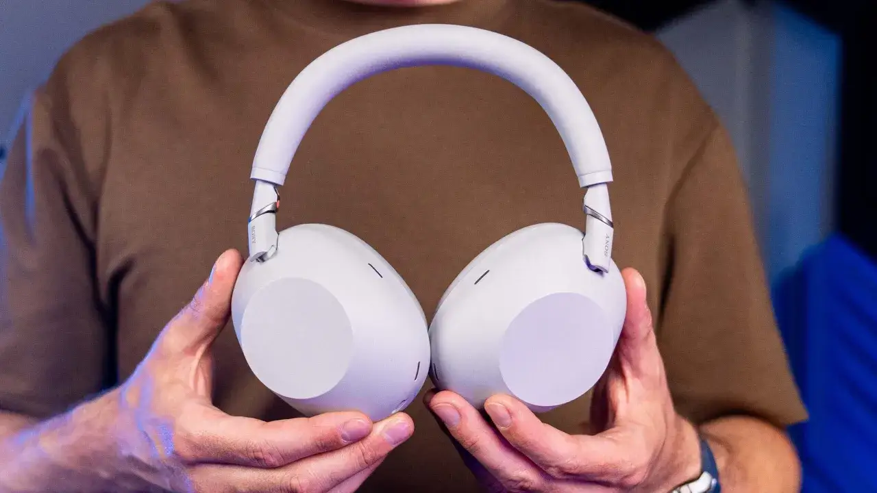 Jasnoszare słuchawki Sony trzymane w dłoniach.