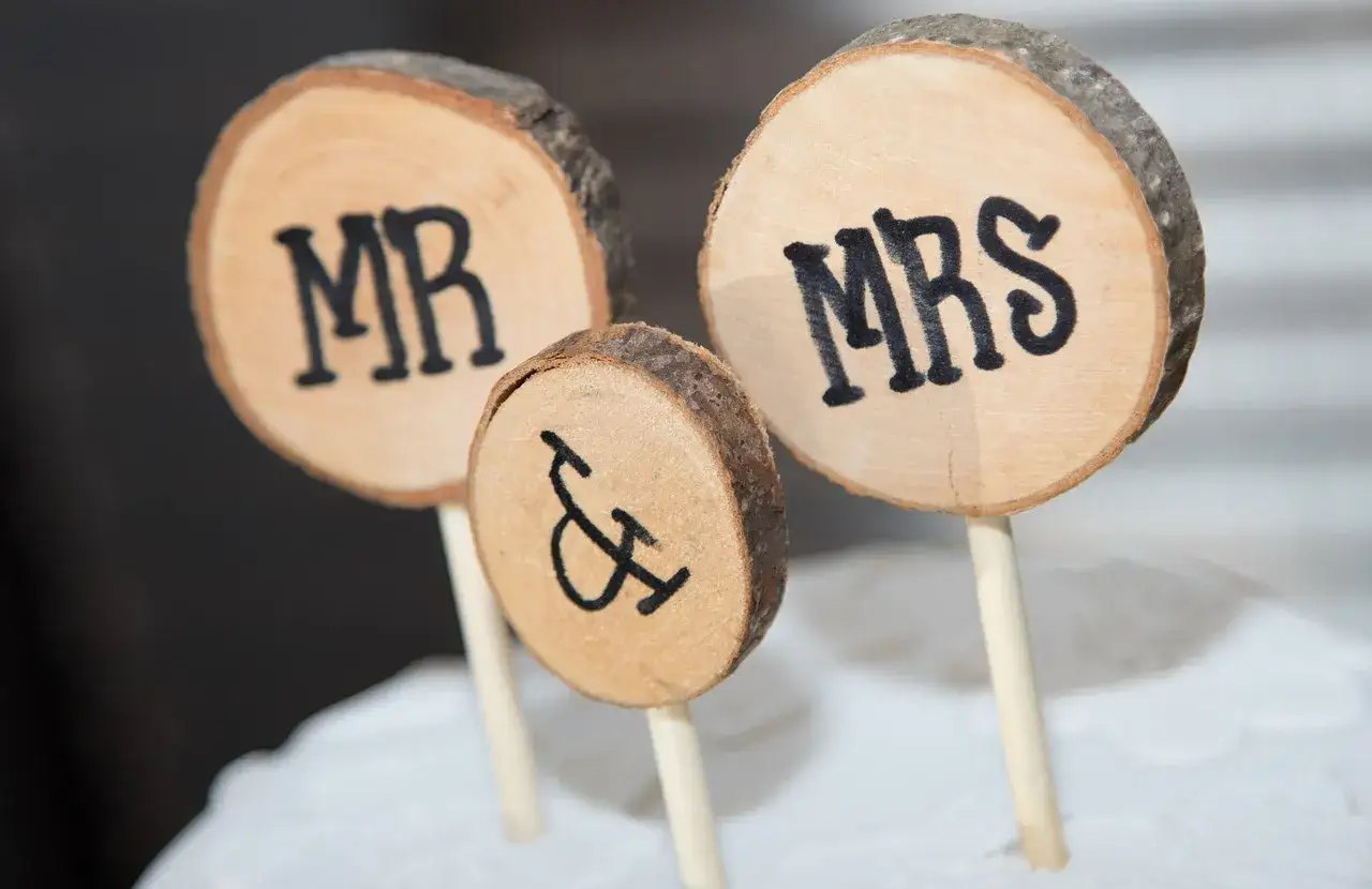 Drewniane krążki z napisami MR i MRS, symbolizujące Parę Młodą, ozdabiają tort.