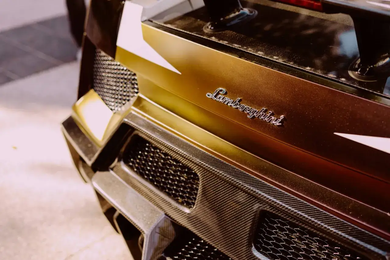 Złote Lamborghini z napisem marki i elementami z włókna węglowego.