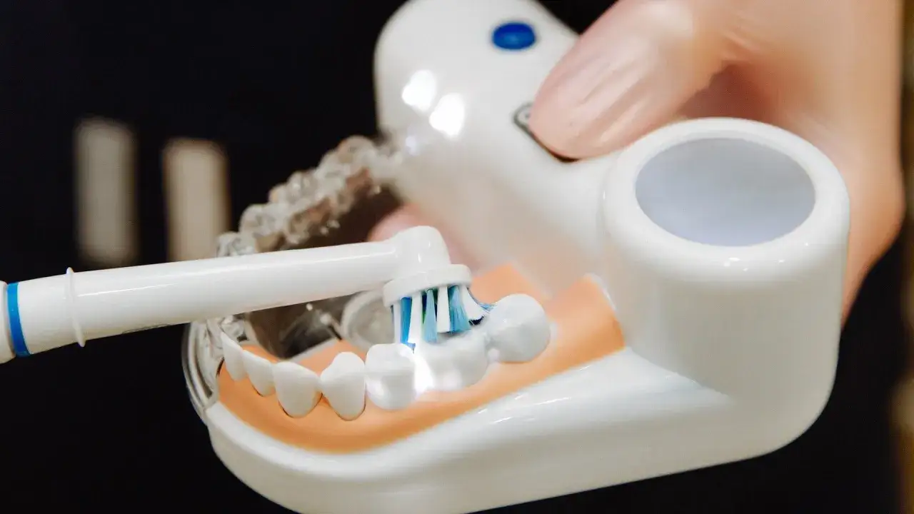 Demonstracja, jak myć zęby szczoteczką elektryczną na modelu. Widać główkę szczoteczki z pastą na zębach.