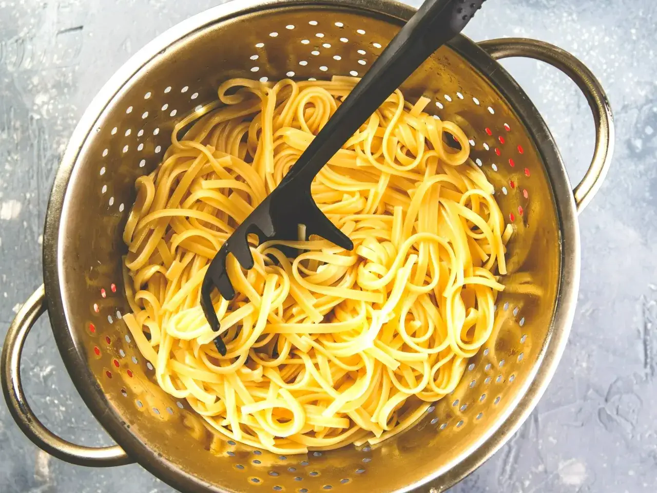 Ugotowany makaron nitki w durszlaku, gotowy do dalszych kulinarnych eksperymentów. Co zrobic z ugotowanego makaronu nitki?
