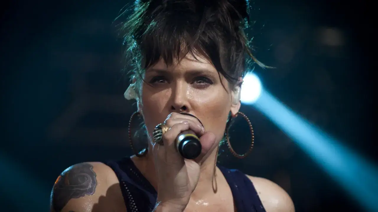 Beth Hart z tatuażem na ramieniu, w okrągłych kolczykach, śpiewa do mikrofonu. Choć nie widać jej dzieci, jej energia na scenie jest jak dla nich.