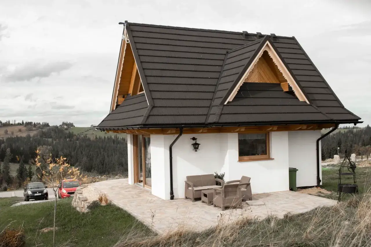 Nowoczesny domek w stylu góralskim w Bukowinie Tatrzańskiej, z tarasem i meblami ogrodowymi, otoczony zielenią i lasem.