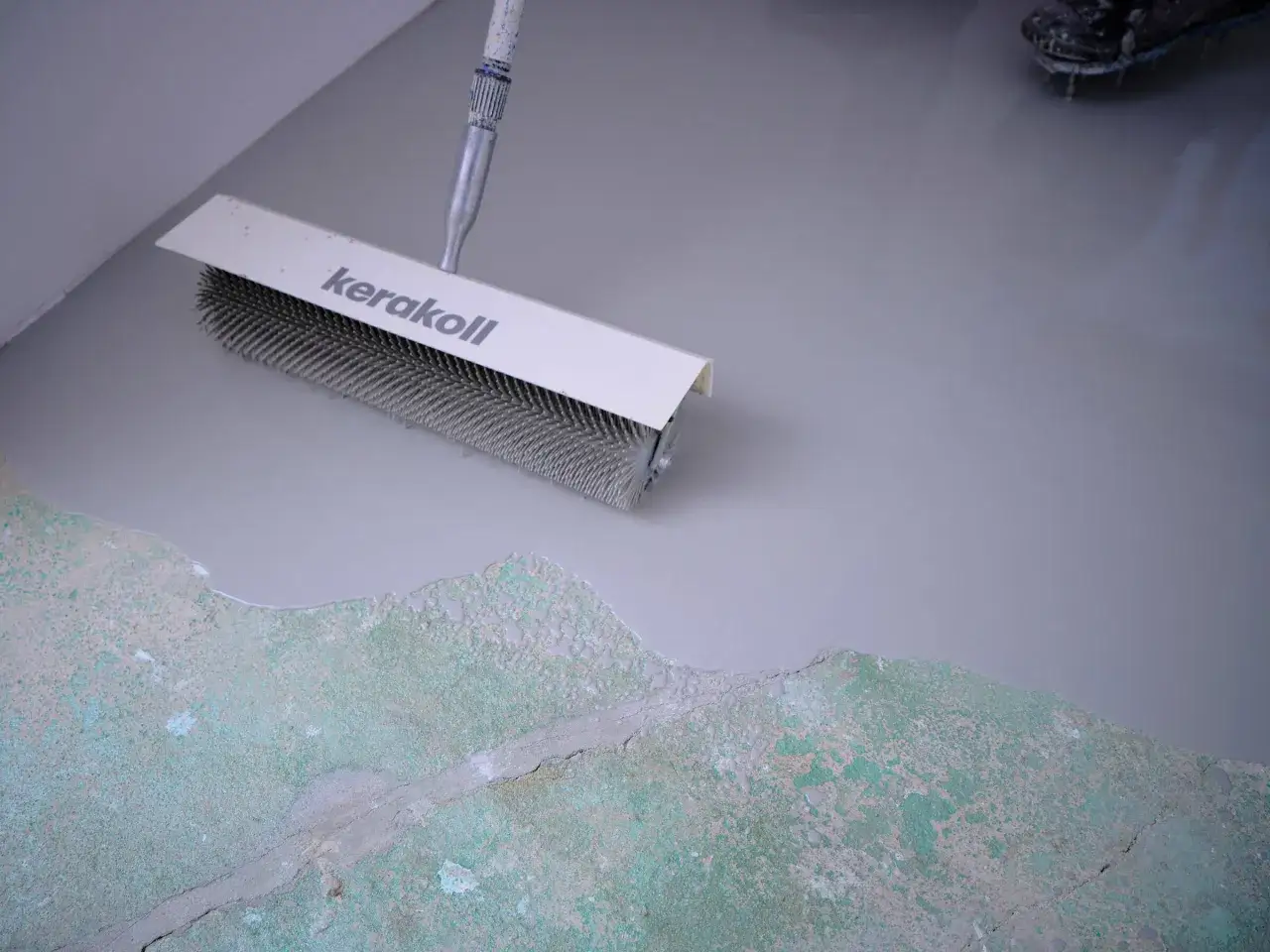 Wałek z kolcami Kerakoll rozprowadza masę samopoziomującą po starej posadzce. To kluczowy etap prac, co po wylewkach.