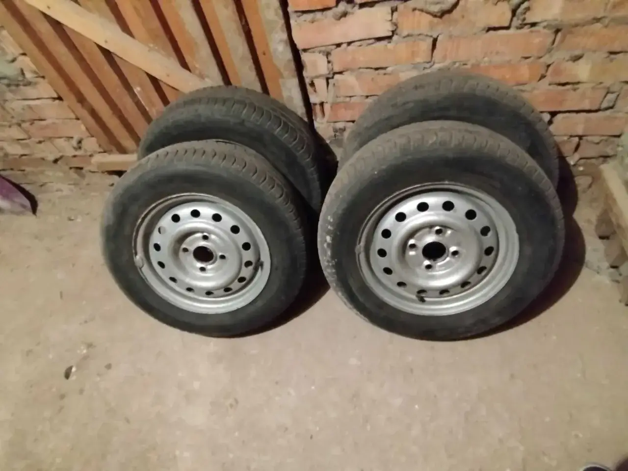 Cztery stalowe felgi z oponami, gotowe do sprzedaży na złomie. Ciekawe, ile za felgę stalową na złomie można dostać.