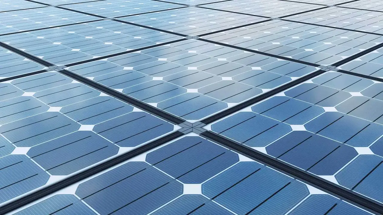 Siatka niebieskich paneli fotowoltaicznych odbija chmury.