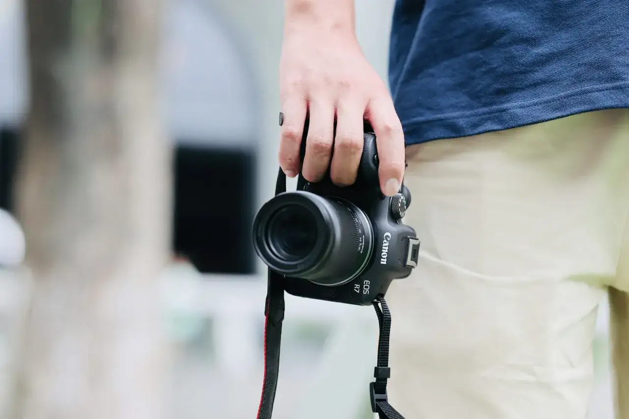 Dłoń trzyma aparat Canon EOS R7, gotowy do uchwycenia chwili. Jego matryca w aparacie zapewni doskonałą jakość zdjęć.