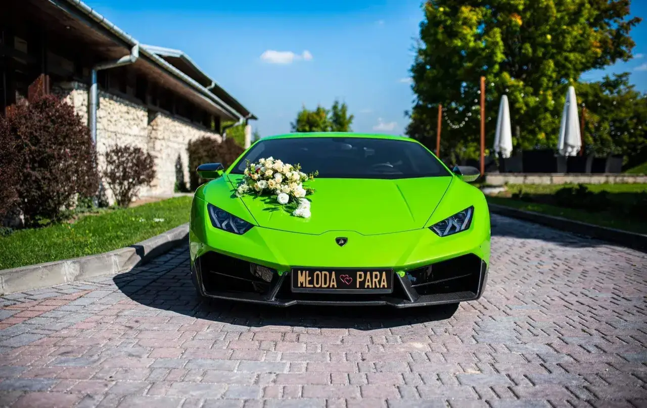 Jaskrawozielone Lamborghini z bukietem kwiatów na masce, zaparkowane na brukowanej nawierzchni.