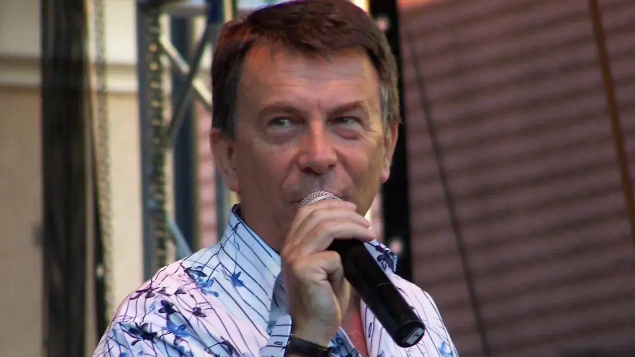 Mężczyzna w koszuli z kwiatowym wzorem śpiewa do mikrofonu. Czy to on, kto śpiewa "Zielone wzgórza nad Soliną"?