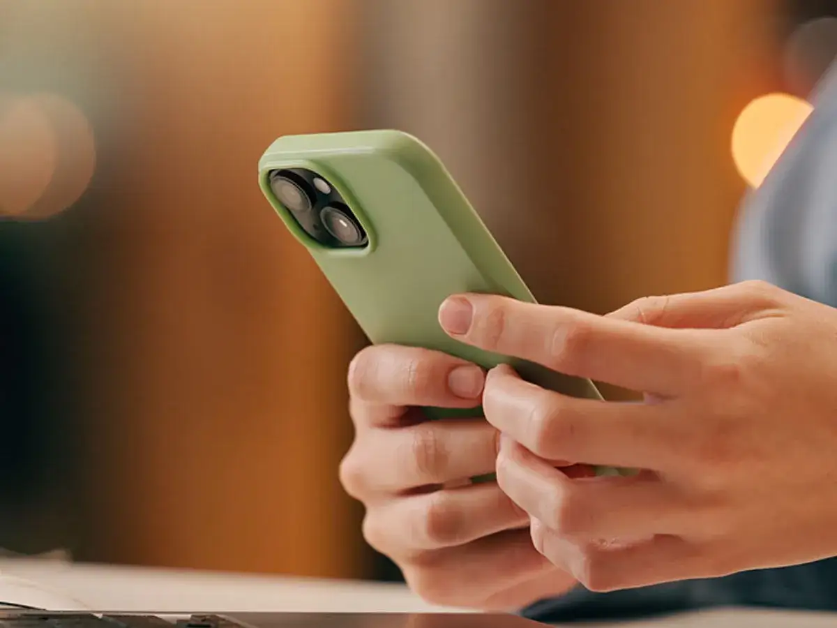 Dłonie trzymające zielony telefon komórkowy.