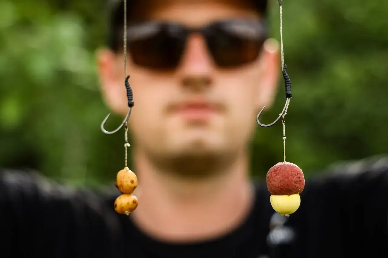 Wędkarz prezentuje przynęty na karpia. Widać dwa zestawy: jeden z dwoma kuleczkami, drugi z kulką czerwono-żółtą. Jaki rozmiar haczyka na karpia?