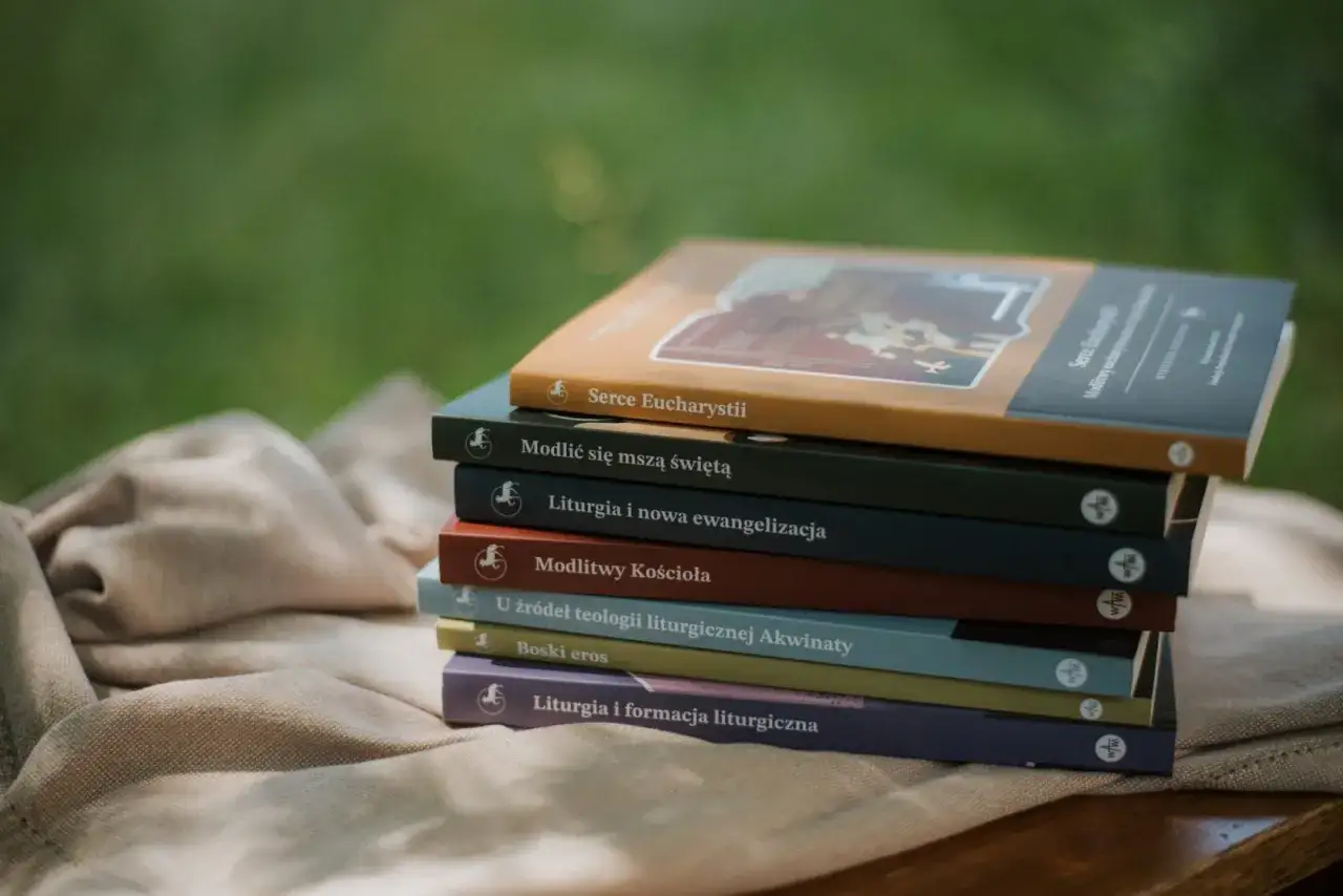 Stos książek o tematyce religijnej, w tym "Serce Eucharystii", na tle zieleni.