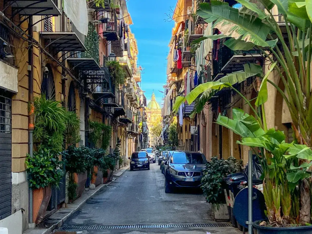 Wąska uliczka w Palermo, z kolorowymi kamienicami, balkonami pełnymi prania i zielenią. Czy warto tu przyjechać? Zdecydowanie tak!