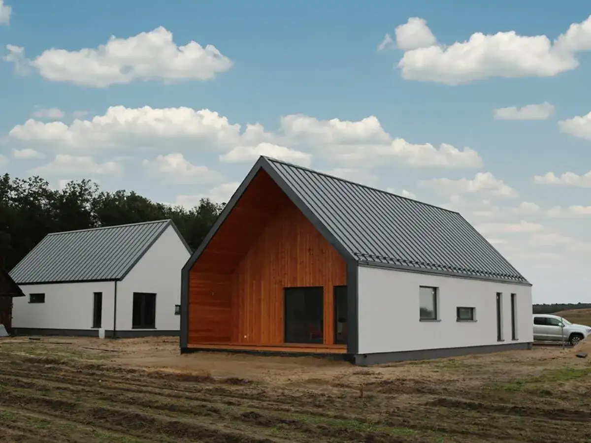 Dwa nowoczesne domy z szarym dachem i białymi ścianami, jeden z drewnianą elewacją.