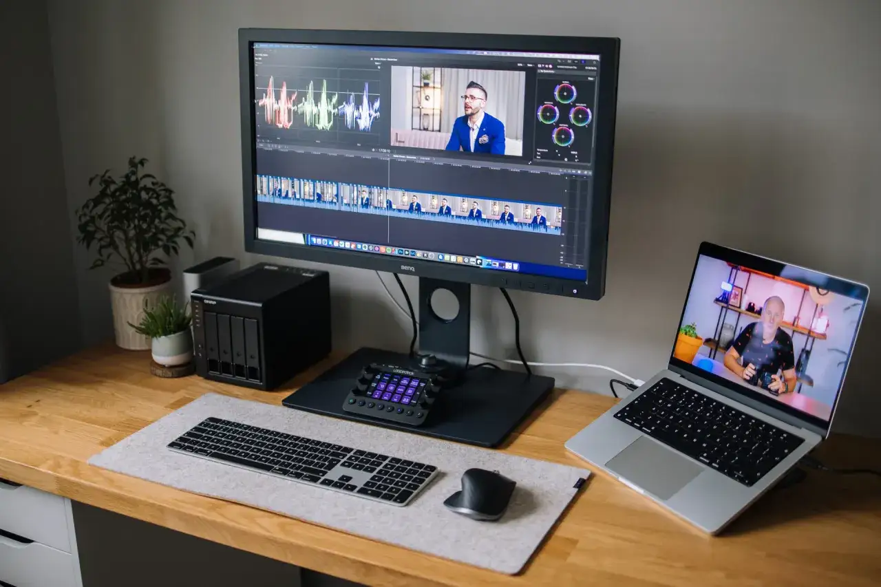 Stacja do edycji wideo z monitorem BenQ, laptopem, klawiaturą i kontrolerem. Na ekranie widać oś czasu i wykresy, co sugeruje pracę nad parametrami monitora.