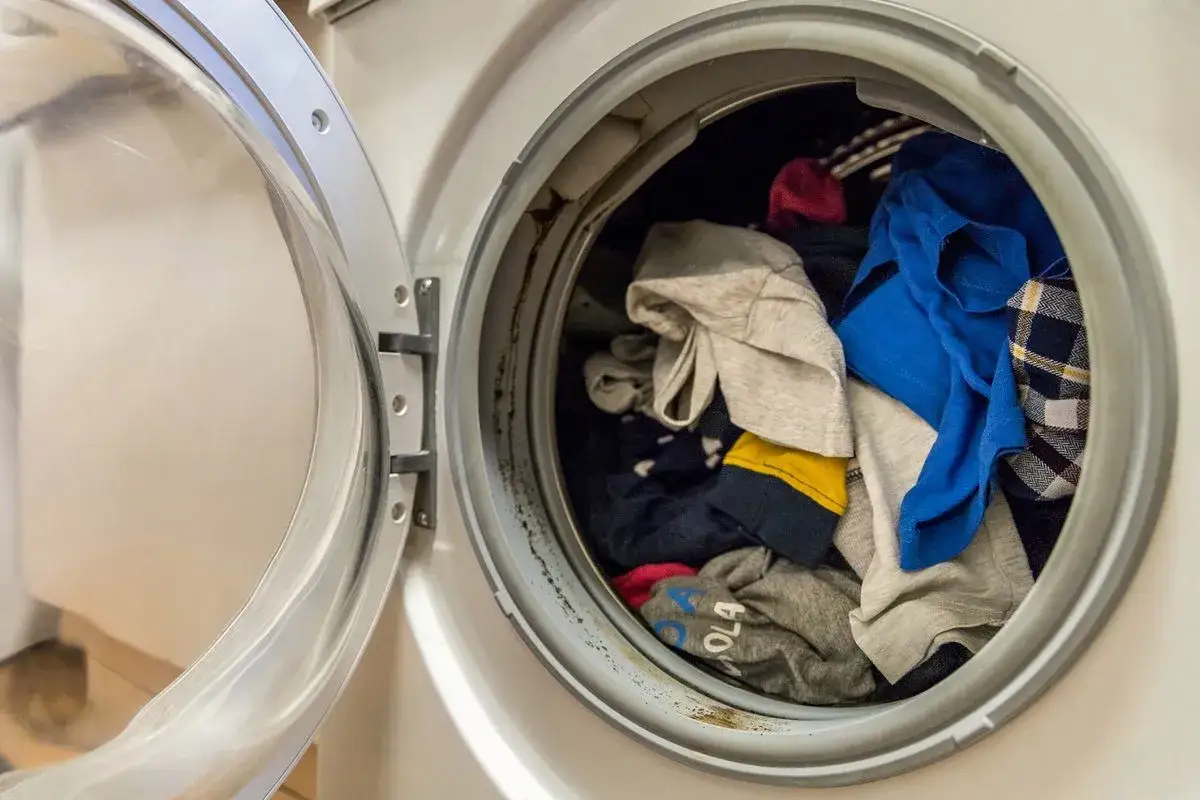 Otwarta pralka z wsadzonym praniem, w tym kolorowymi ubraniami.