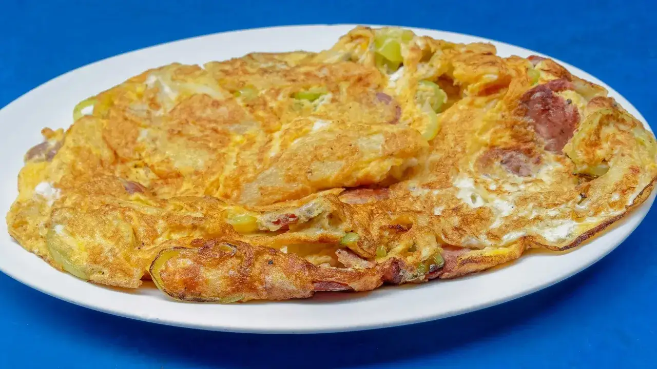 Złocisty omlet z warzywami i kawałkami kiełbasy, idealny przykład, jak się robi omlet dietetyczny.