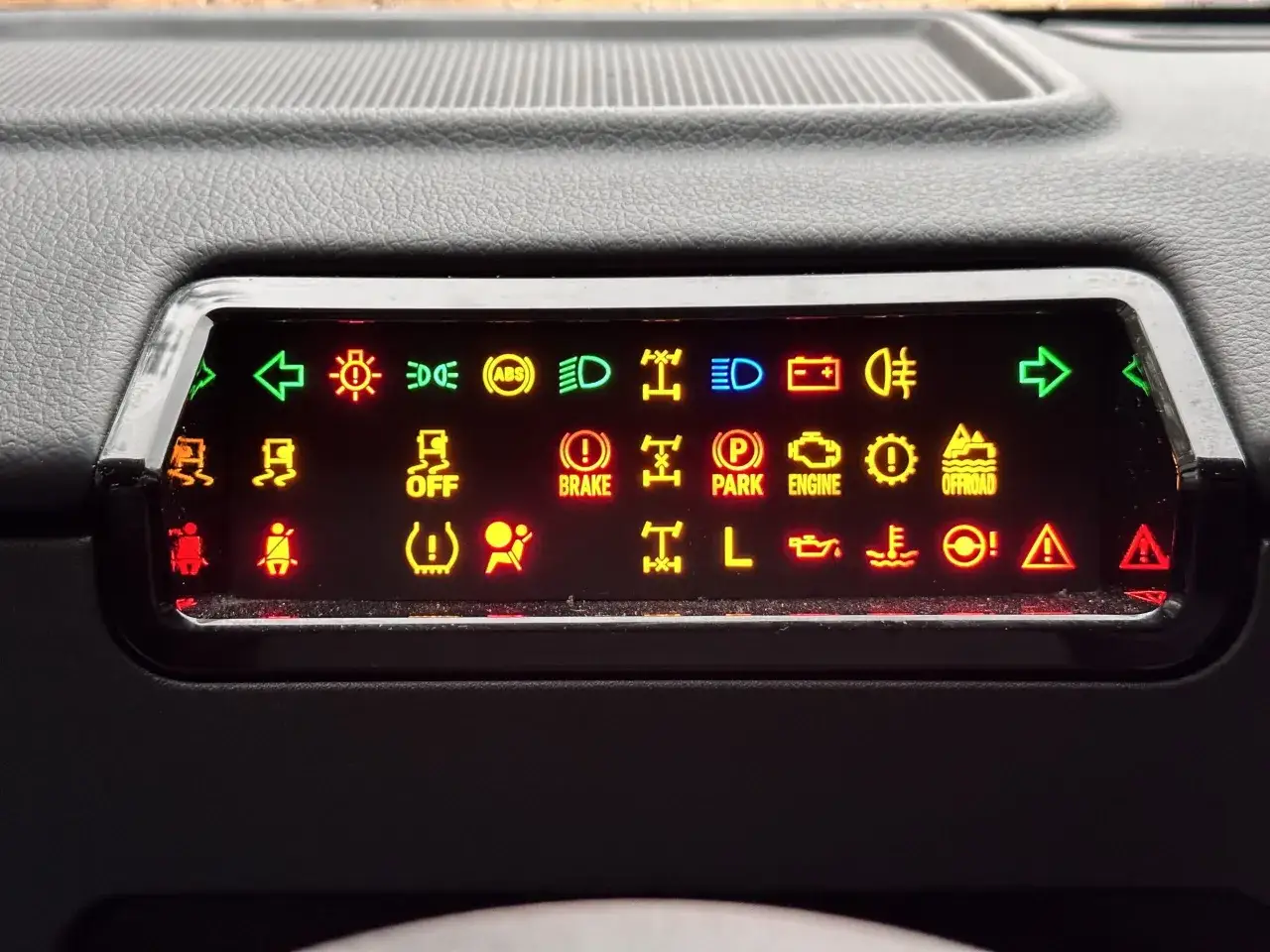 Panel kontrolny samochodu z wieloma świecącymi kontrolkami ostrzegawczymi w różnych kolorach.