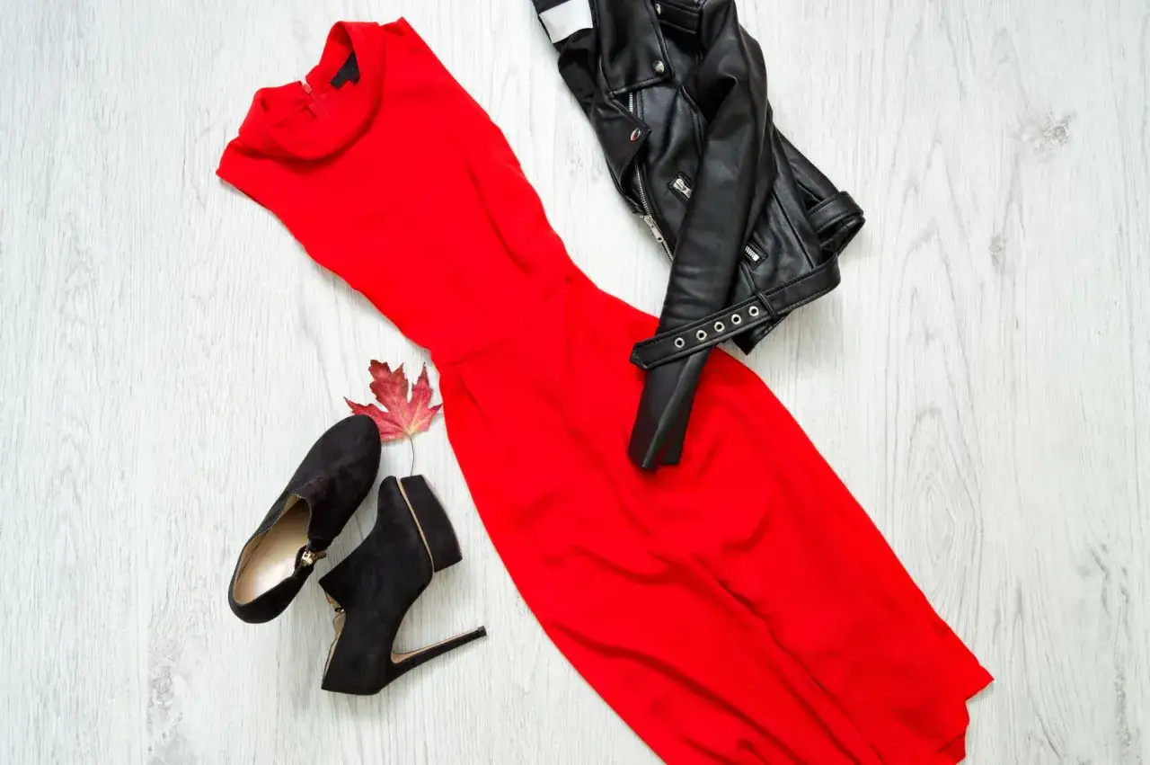 Czerwona sukienka wieczorowa, czarna ramoneska i zamszowe botki. Inspiracja, jak dobrać buty do sukienki wieczorowej, by stworzyć odważny look.