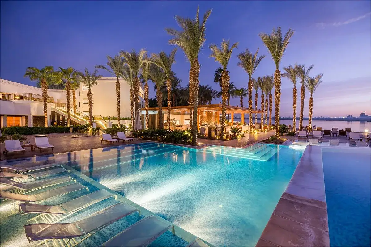 Luxury resort pool with palm trees and lounge chairs at dusk.