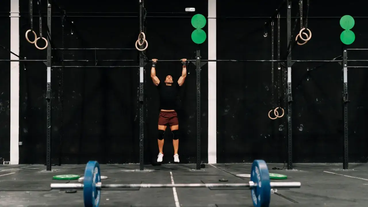 Mężczyzna wykonuje podciąganie na drążku w siłowni CrossFit.