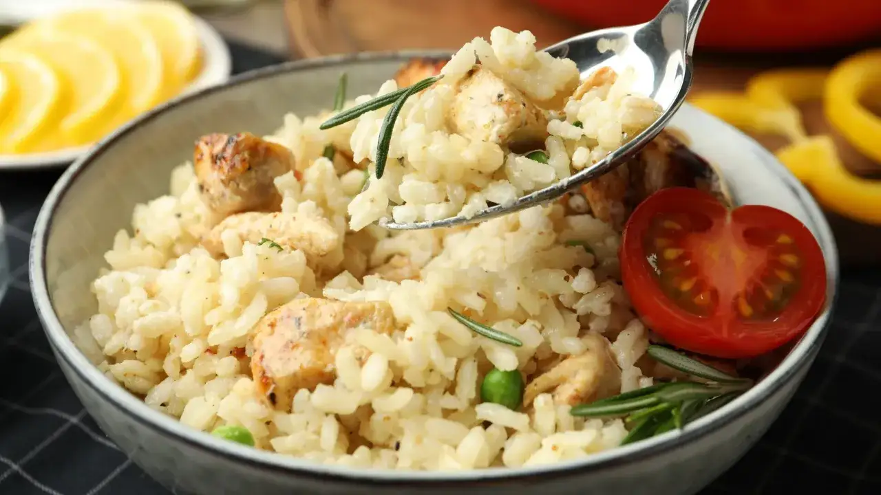 Kremowe risotto z kurczakiem, groszkiem i rozmarynem, udekorowane pomidorkiem. Idealne na obiad.