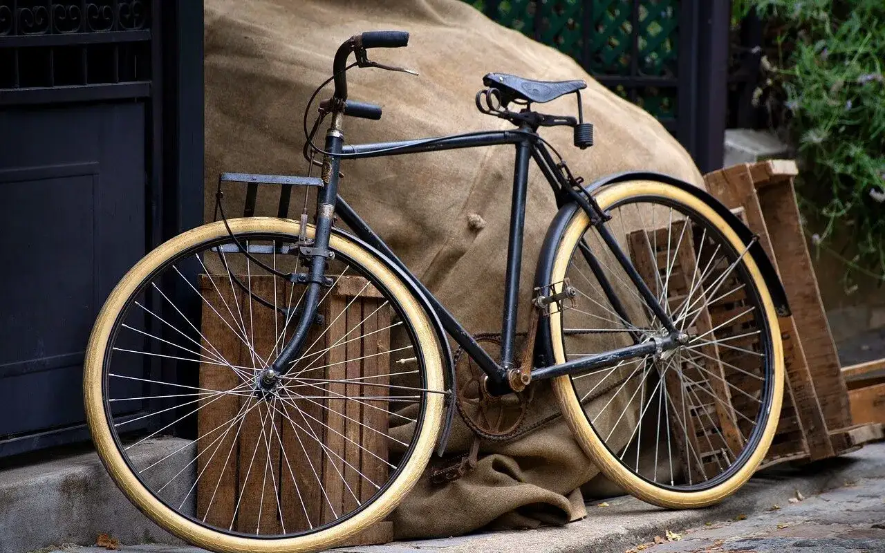 Stary rower z kremowymi oponami, gotowy do jazdy. Jego kadencja rowerowa czeka na przygodę.