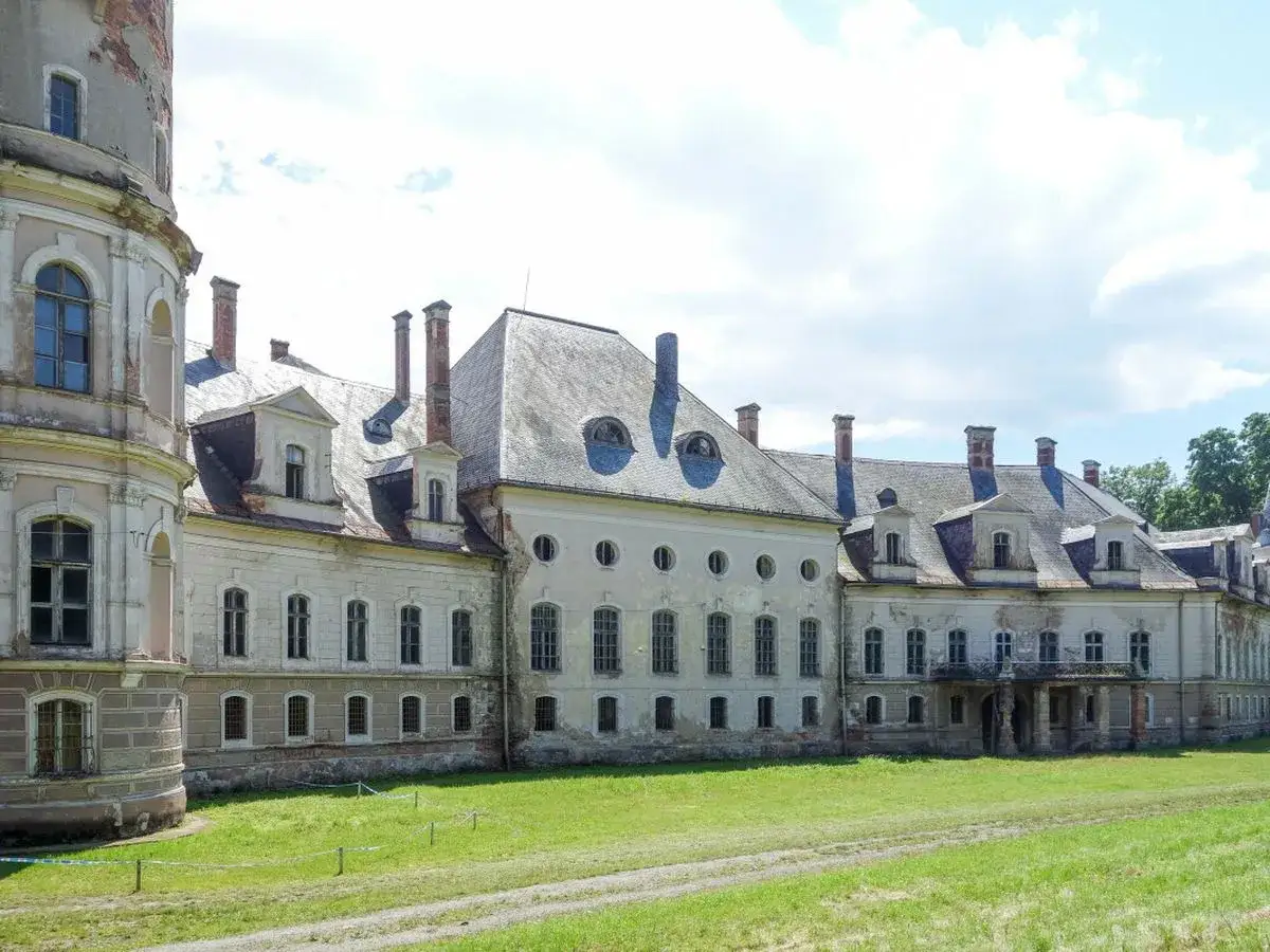 Dawny pałac bożków, zniszczony i opuszczony, z charakterystycznymi okrągłymi oknami i wieżą.