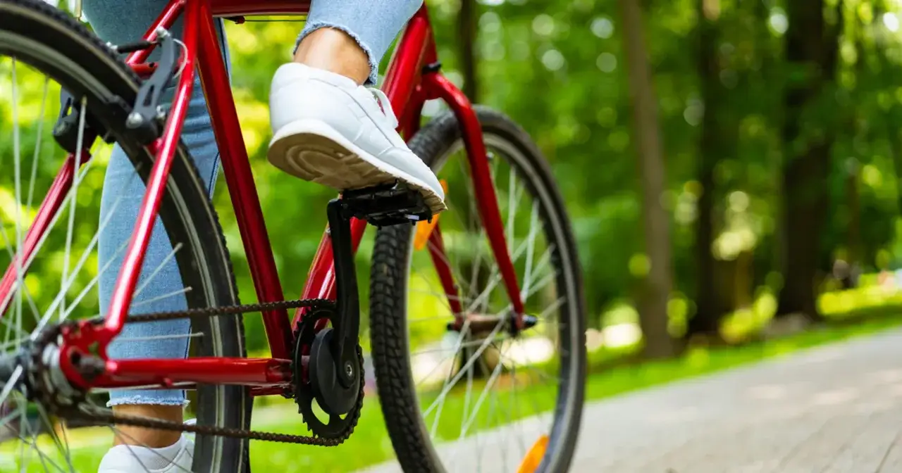 Osoba na czerwonym rowerze, gotowa do jazdy. Dowiedz się, jak obliczyć waty na rowerze, by śledzić swoje postępy.