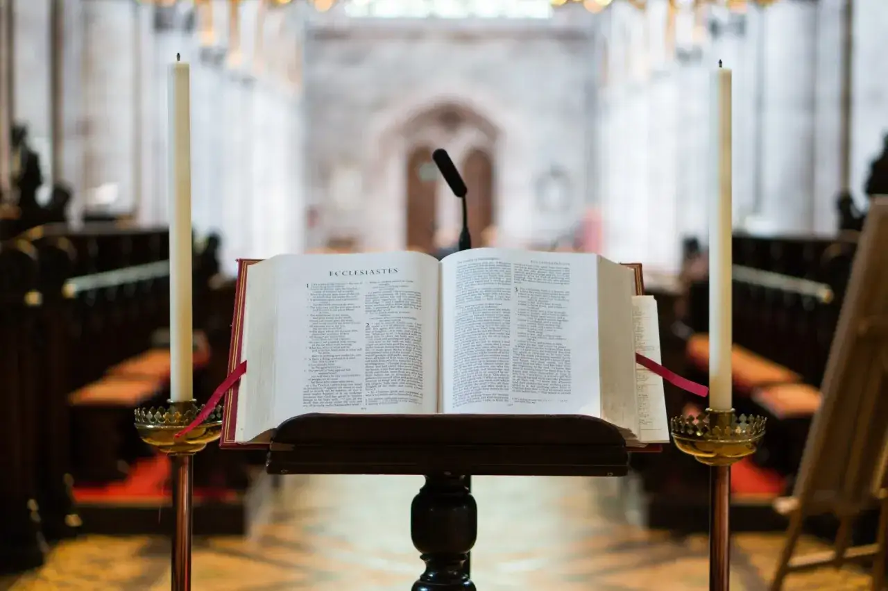 Otwarta Biblia na pulpicie, obok świece, w kościele.