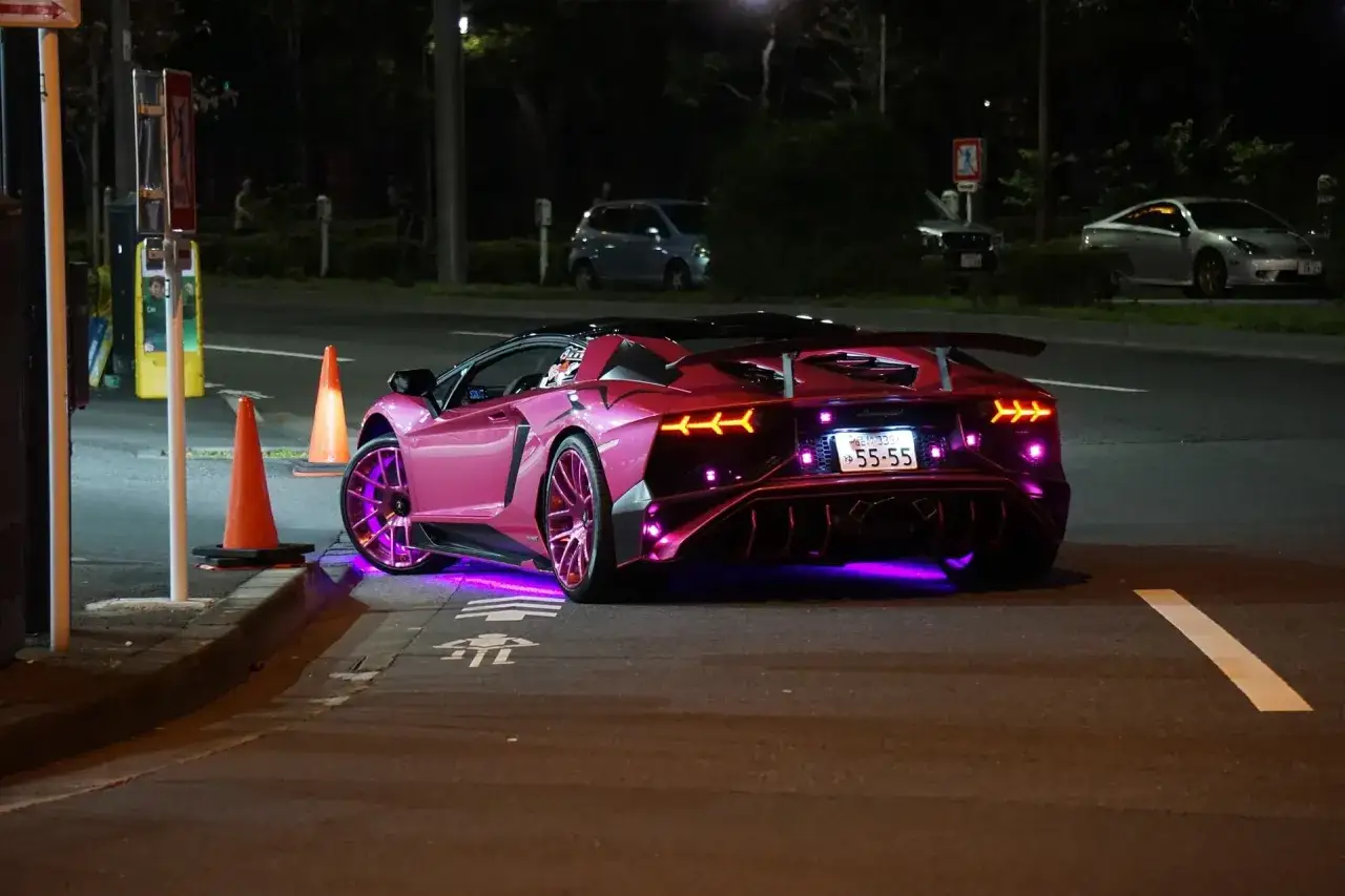 Różowy Lamborghini z neonowym podświetleniem na ulicy nocą.