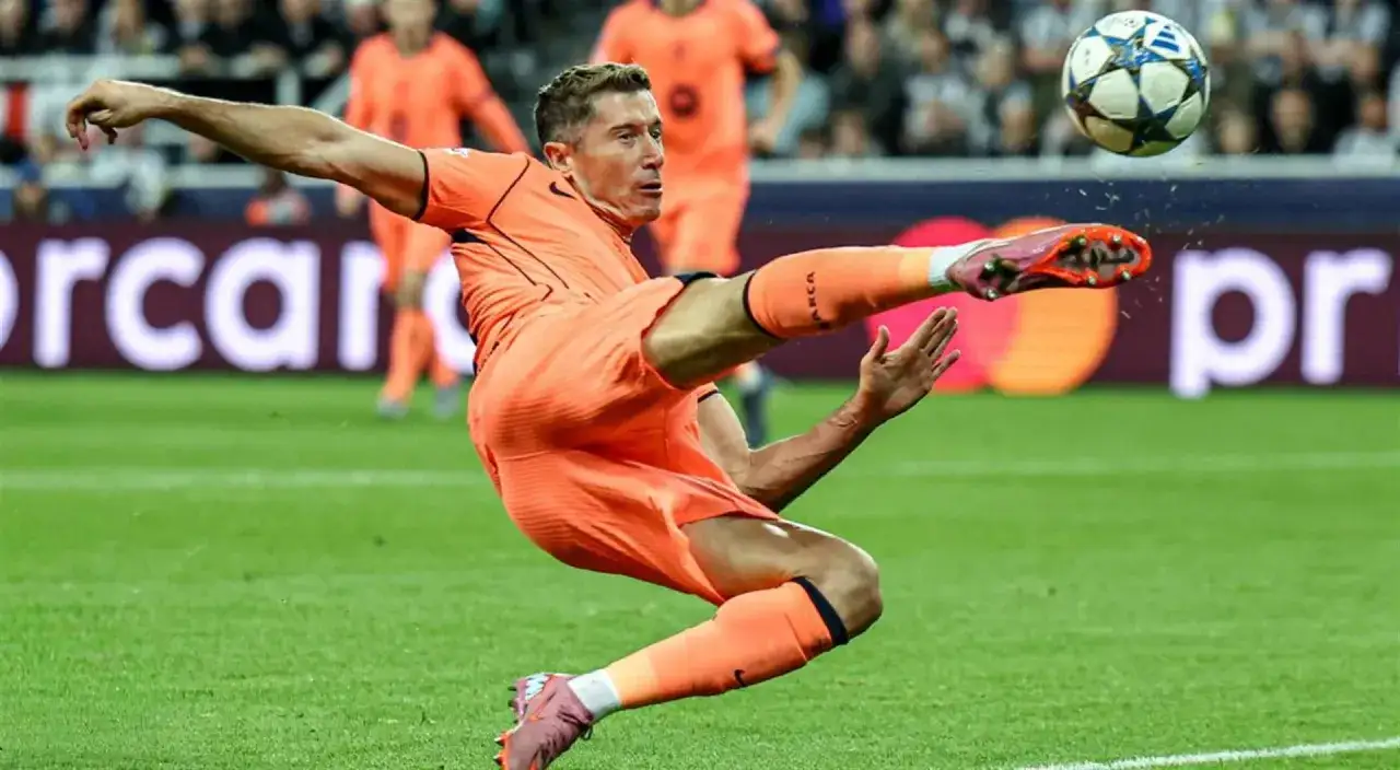 Piłkarz w pomarańczowym stroju wykonuje akrobatyczne kopnięcie do piłki. To Robert Lewandowski, który gra w Lidze Mistrzów.