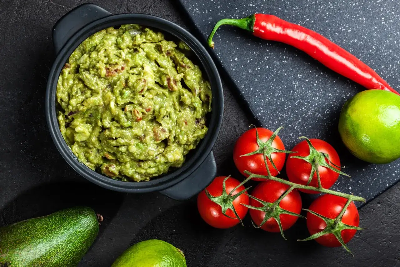 Miseczka guacamole z awokado, pomidorkami, limonką i papryczką chili.
