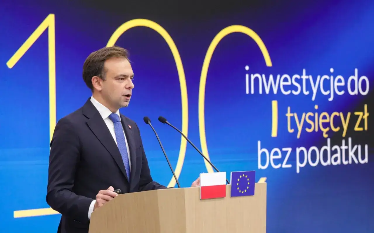 Mężczyzna w garniturze przemawia na tle napisu "inwestycje do tysięcy zł bez podatku". Czy od obligacji płaci się podatek?