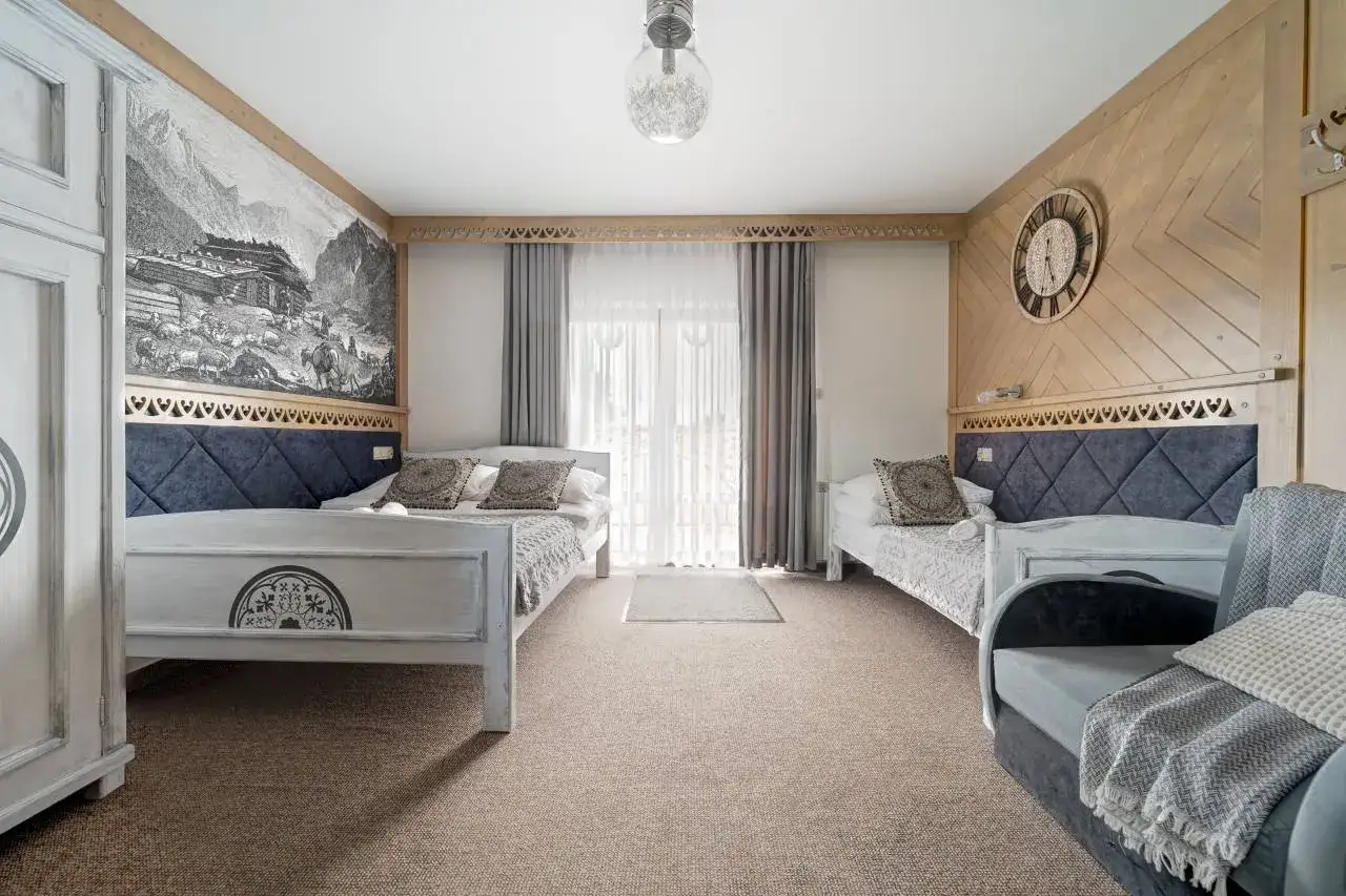 Pokoje gościnne Zosia Bukowina Tatrzańska: przytulne wnętrze z dwoma łóżkami, góralskim motywem na ścianie i widokiem na góry.