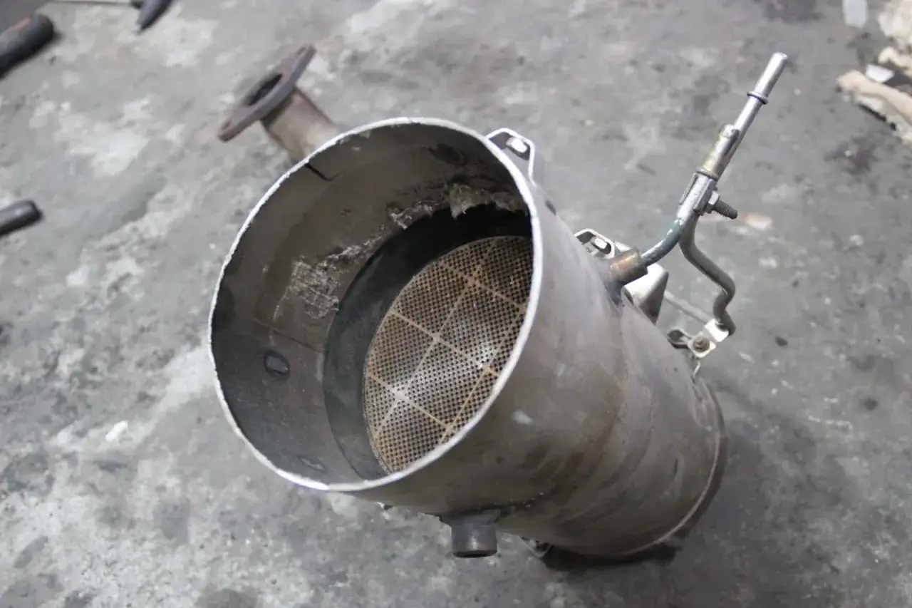 Filtr DPF z widocznym wkładem ceramicznym i rurką.