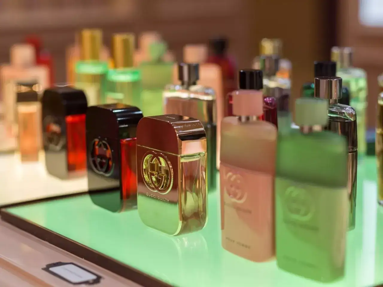 Butelki perfum Gucci Guilty na zielonym podświetlanym tle.