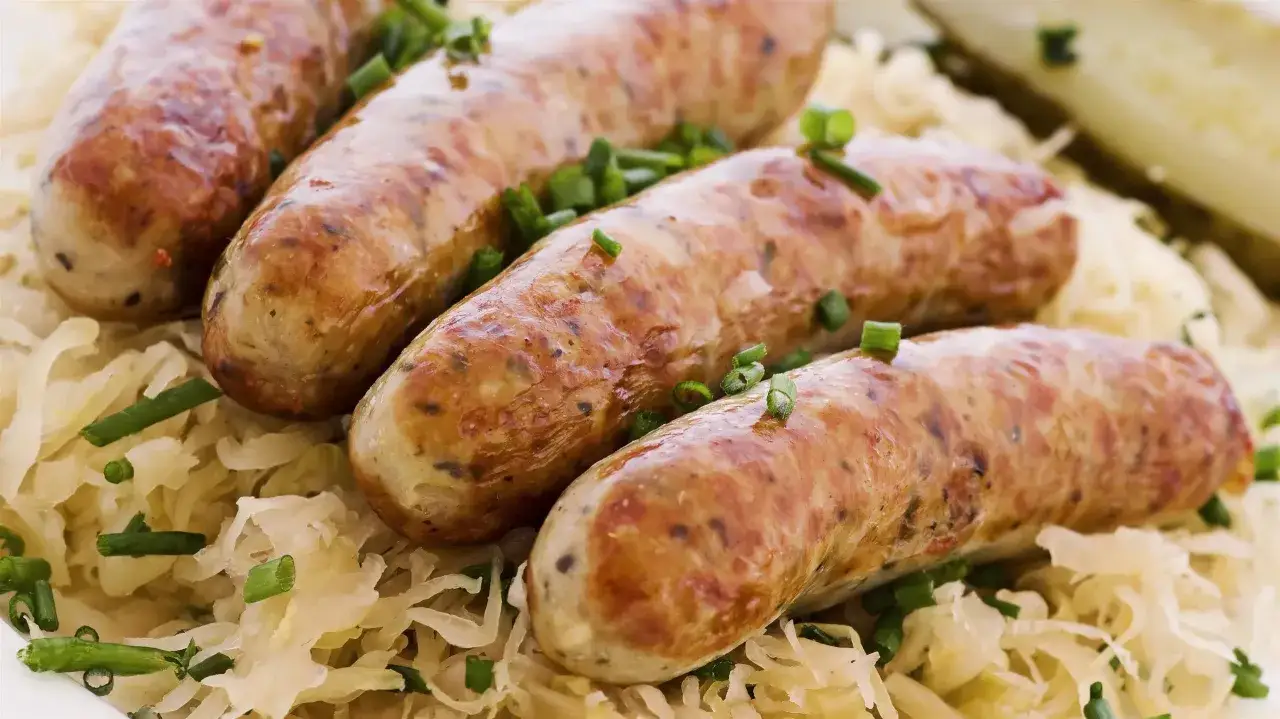 Aksamitna biała kiełbasa w kiszonej kapuście, posypana szczypiorkiem. Pyszne danie gotowe do podania.