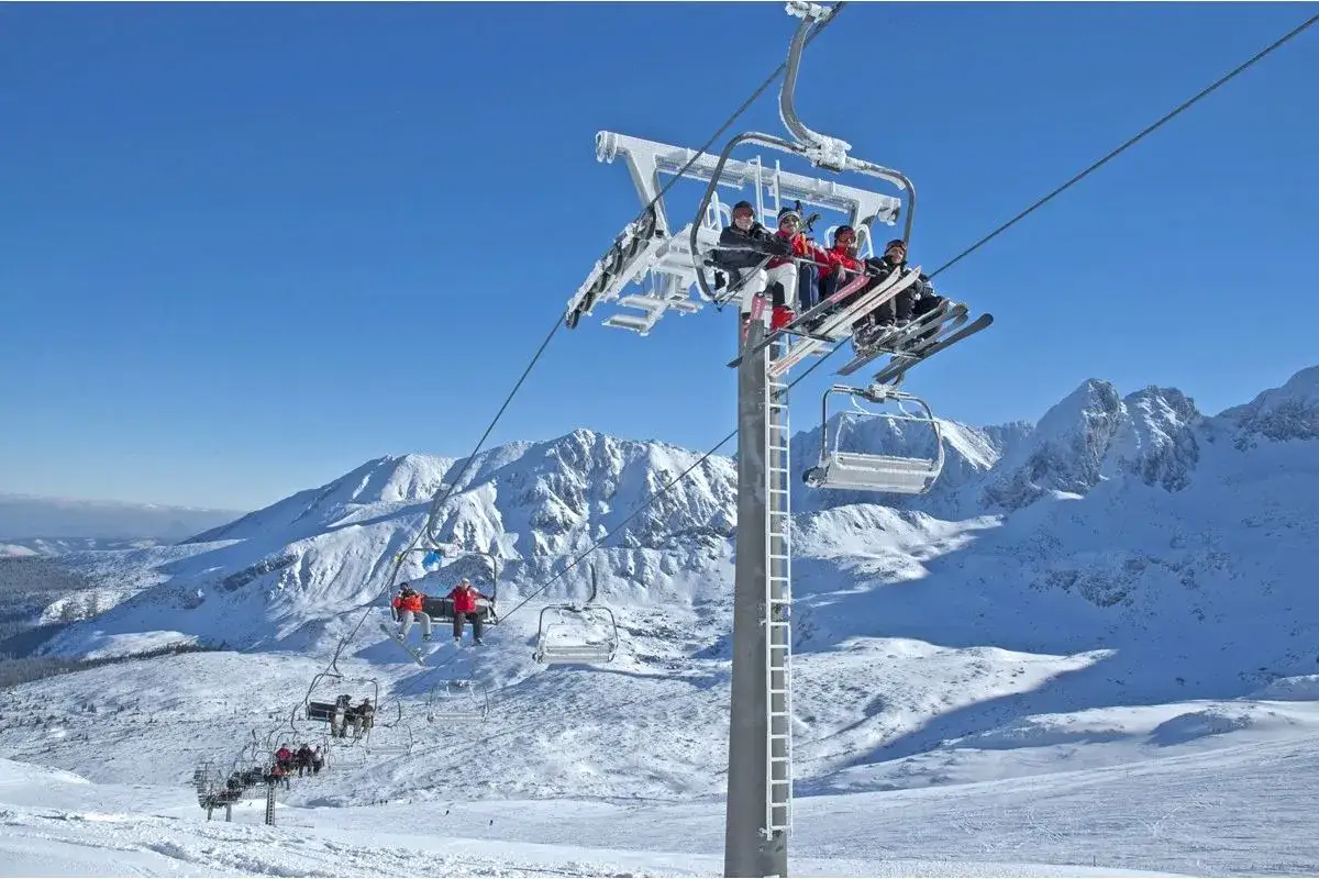 Kasprowy Wierch trasy narciarskie. Ludzie na wyciągu krzesełkowym podziwiają zimowy krajobraz Tatr.